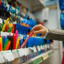 School girl choosing a pen at the shelf in stationery store. Female child buying office supplies in shop, schoolchild in supermarket